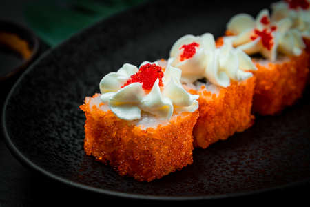 Japanese rolls with caviar and philadelphia cheese on a black plate close-up, selective focusの写真素材
