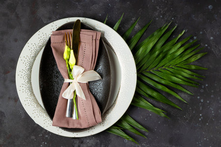 Wedding table setting concept. Plate, cutlery on linen napkin and flowers, top view, vertical photo
