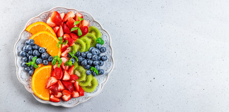 Web banner with fresh summer salad of various fruits and berries. Kiwi, orange, strawberry and...