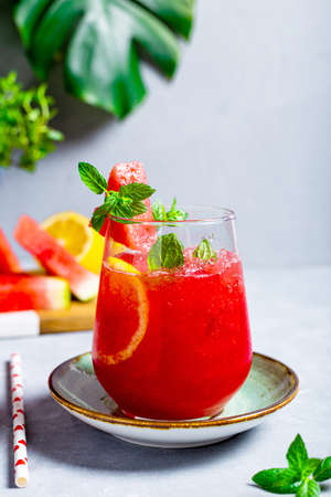 A glass of refreshing summer fresh watermelon with lemon and mint on light gray background, vertical photoの写真素材