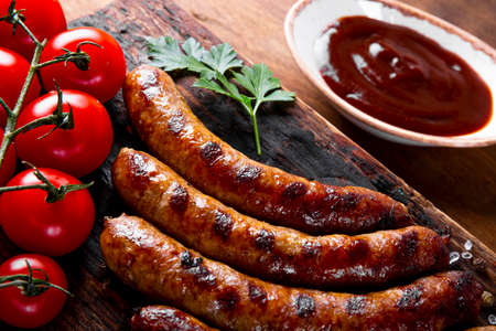 Grilled minced beef and pork sausages with barbecue sauce on wooden board close upの写真素材