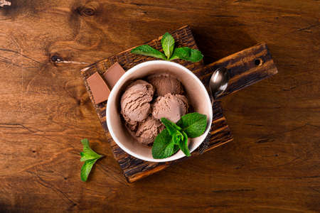 Balls of homemade chocolate ice cream with mint in a bowl on the wooden background top viewの写真素材