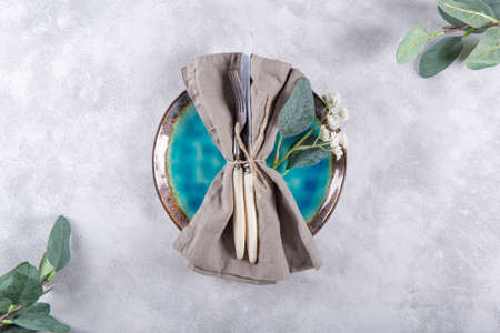 Wedding table setting concept. Plate, cutlery on linen napkin and flowers on the light gray background, top viewの写真素材