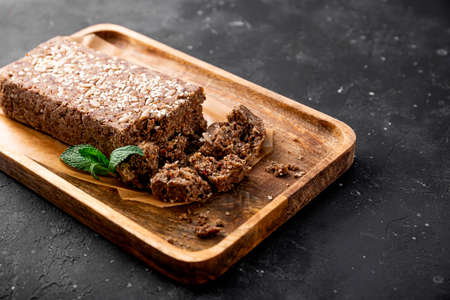 Healthy Vegan Sweets, Sugar Free Nuts Halva with Seeds and Sesame on the wooden plate and dark gray background close upの写真素材