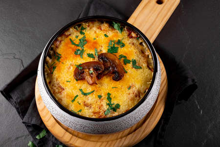 Julienne with potatoes and mushrooms in a baking dish on a dark background, close up. Traditional French dishの写真素材