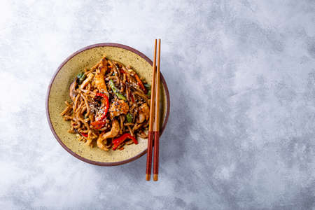 Plate of asian buckwheat soba noodles with vegetables, mushrooms and chicken on light gray background with free space for textの写真素材