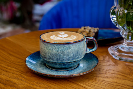 A cup of cappuccino coffee and flowers on a table in a cafe
