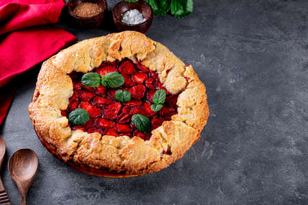 Homemade pie with strawberries on the table, summer pastries with berries, photo with copy space for textの写真素材