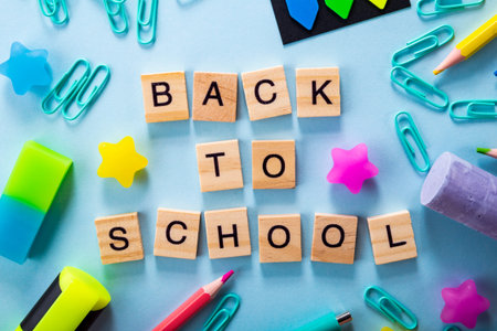 Stationery and lettering back to school in english, blue background. High quality photo