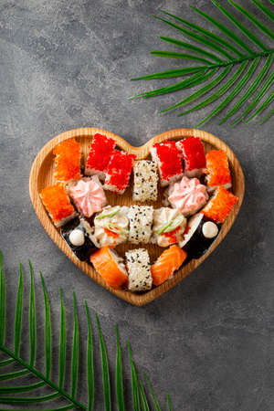 Japanese rolls in heart shaped plate on gray concrete background top view vertical photoの写真素材