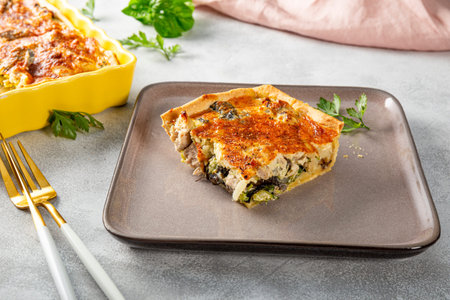 A piece of traditional homemade Lorraine pie with chicken, broccoli and mushrooms on a table