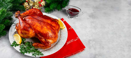 Whole baked chicken or turkey in a sauce with paprika on a plate and a Christmas table setting, banner for website with copy space for text. High quality photoの写真素材