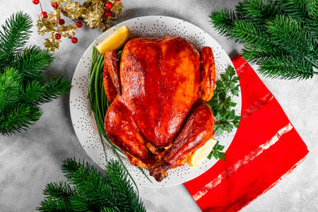 Whole baked chicken in sauce with paprika on a plate and a Christmas table setting top view. High quality photoの写真素材