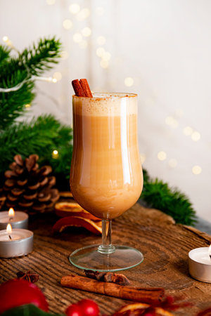 A glass of traditional Christmas drink eggnog on a festive table, vertical photo. Spicy drink made...