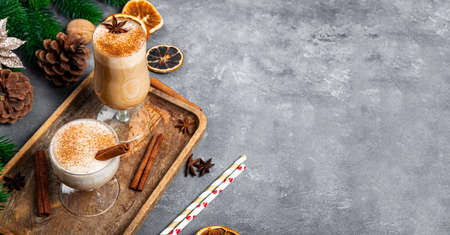 Two glasses of traditional Christmas drink eggnog on a gray background, web banner with copy space for text. Spicy drink made from egg and milk with cinnamon, cardamom. High quality photoの写真素材