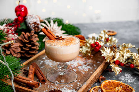 A glass of traditional Christmas drink eggnog on a festive table, copy space for text. Spicy drink made from egg and milk with cinnamon, cardamom. High quality photoの写真素材