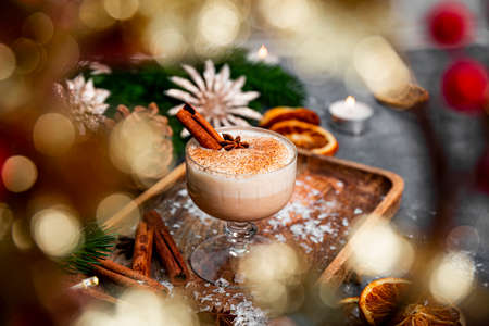 A glass of traditional Christmas drink eggnog on a festive table, selective focus. Spicy drink made from egg and milk with cinnamon, cardamom. High quality photoの写真素材