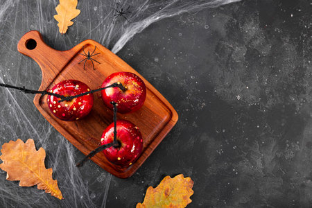 Red apples in caramel with a festive Halloween decor top view, an original treat for a festive Halloween table decorated with spiders and cobwebs, copy space for text. High quality photoの写真素材