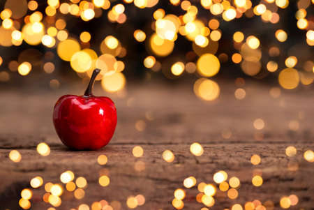 Festive New Year card with free space for text. Red Christmas apple on a dark background with beautiful golden bokeh, soft focusの写真素材