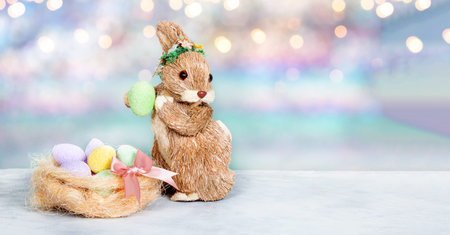 Easter bunny, colored eggs and pink flowers. Festive easter web banner with free text spaceの写真素材
