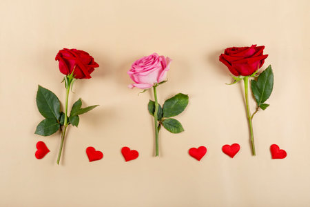 Three roses and red hearts on beige background, top view. Greeting card for Valentines day