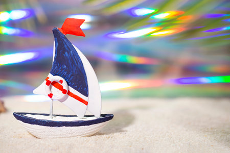 Toy boat and on white sea sand. Vacation concept by the sea with free space for textの写真素材