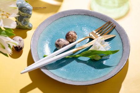 Table setting for celebrating easter. Plate, cutlery, eggs and spring flowers on the yellow table...