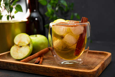 A glass of refreshing apple cider with cinnamon and ice on the dark tableの写真素材