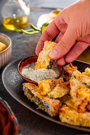 Healthy zucchini fries with yogurt and herbs sauce in the hand. High quality photoの写真素材