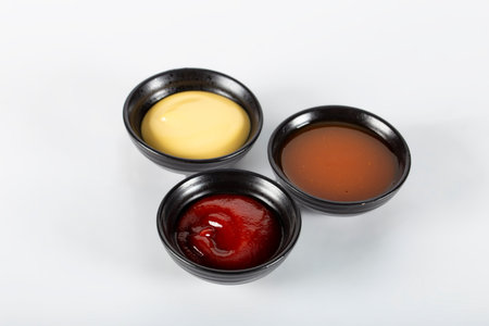 Three different sauces on a white background, ketchup, cheese sauce and chili sauce. High quality...
