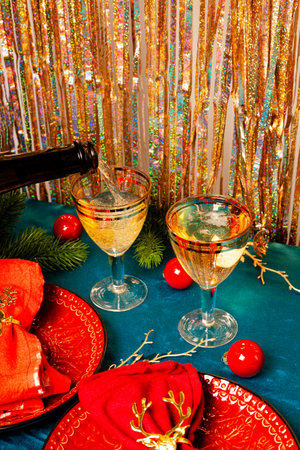 Modern Christmas table setting, red plates with napkins and two glasses of champagne on the festive table vertical photo copy space for text. High quality photoの写真素材