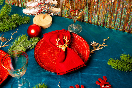 Modern Christmas table setting, red plates with napkins and two glasses on the festive table. High quality photoの写真素材