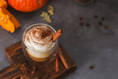 A glass of autumn pumpkin latte with whipped cream and spices. Coffee with pumpkin and cinnamon on a dark background, copy space. High quality photoの写真素材