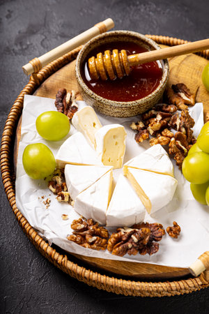 A colorful cheese platter with honey, sweet grapes, and crunchy walnuts, perfect for any gathering or celebration, appetizer for wine, snack board, vertical photoの写真素材