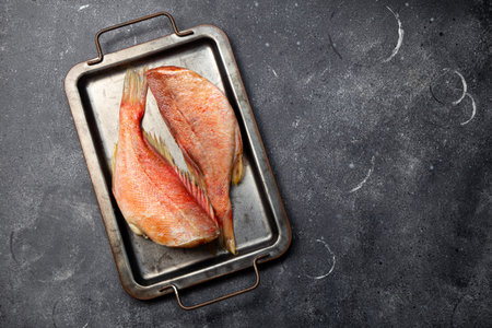 Raw red sea bass or perch top view, black seafood food background with copy space. High quality...