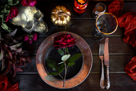 Served table with autumn decor, red roses, and pumpkin. Halloween dinner table setting top view. High quality photoの写真素材