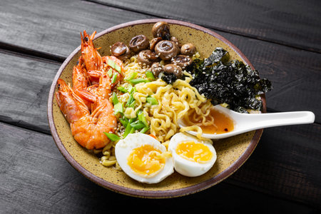 Asian ramen with shrimp, mushrooms, egg and greens on dark wooden table. High quality photo