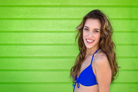 Attractive young woman in a blue bikini, with a green background. Outdoors.の写真素材