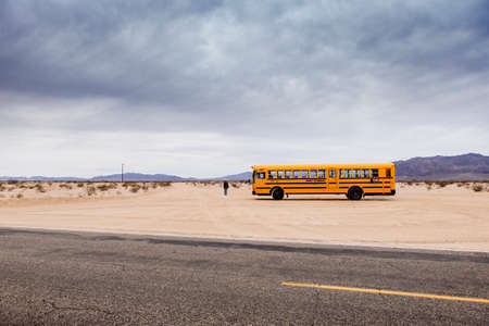 29 Palms, California/USA-03/21/2016: School Bus in the desert, 29 palms,  Boy is walking towards the horizon.のeditorial素材
