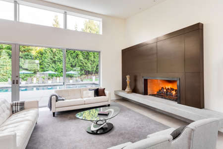 Beautiful living room in luxury home with fireplace, tv, couches, and glimpse of backyard patioの写真素材