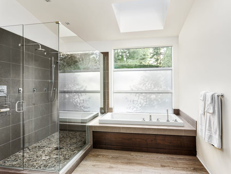 Bathroom interior in new luxury home: bathtub with walk in curbless tile shower, with all glass door and walls.の写真素材