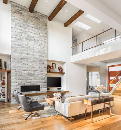 living room interior with hardwood floors and fireplace in new luxury home with vaulted ceiling, loft area, and entrywayfoyerの写真素材