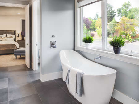 Bathtub in master bathroom in new luxury home with view of master bedroom and neighborhood with trees  through windowの写真素材