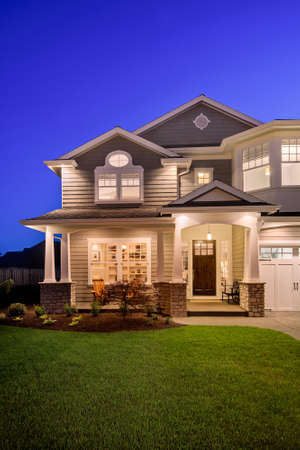 new luxury home at night with beautiful green lawn and covered porchの写真素材