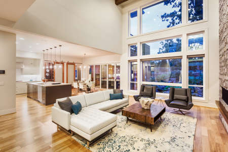 large living room with vaulted ceilings in new luxury home, with large bank of windows, view of kitchen and furnishingsの写真素材