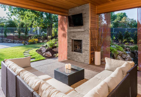 Beautiful Covered Patio with Fireplace, Television, and View of Landscaped Yard as Part of New Luxury Homeの写真素材