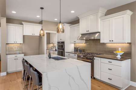 Kitchen in new luxury home with waterfall isalnd, stainless steel appliances, pendant lights, and hardwood floorsの写真素材