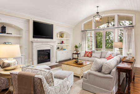 Beautiful living room in new traditional style luxury home. Features vaulted ceilings, fireplace with wall mounted tv, french doors leading outside, and elegant furnishings.の写真素材