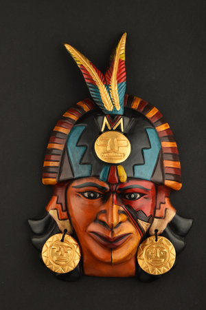Indian Mayan Aztec ceramic mask with feather isolated on black paper background