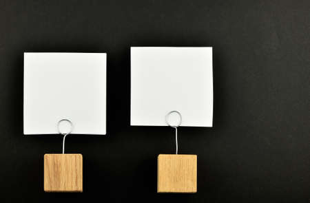 Two white paper notes with wooden holders isolated at black paper background for presentationの写真素材